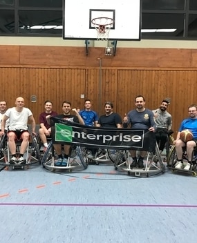 Wheelchair basektball players with Enterprise banner