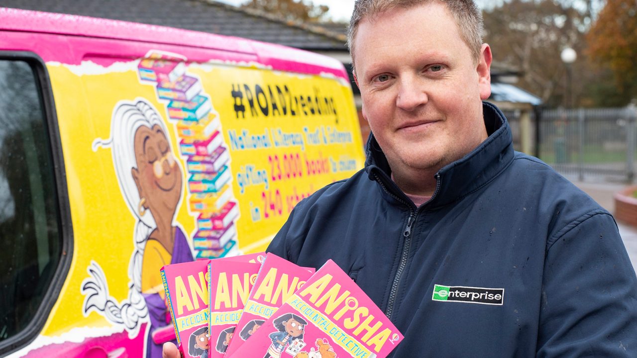 Angestellter steht mit Büchern vor einem Lieferwagen