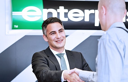 Enterprise Rent-A-Car Management Trainee shaking hands with a customer.