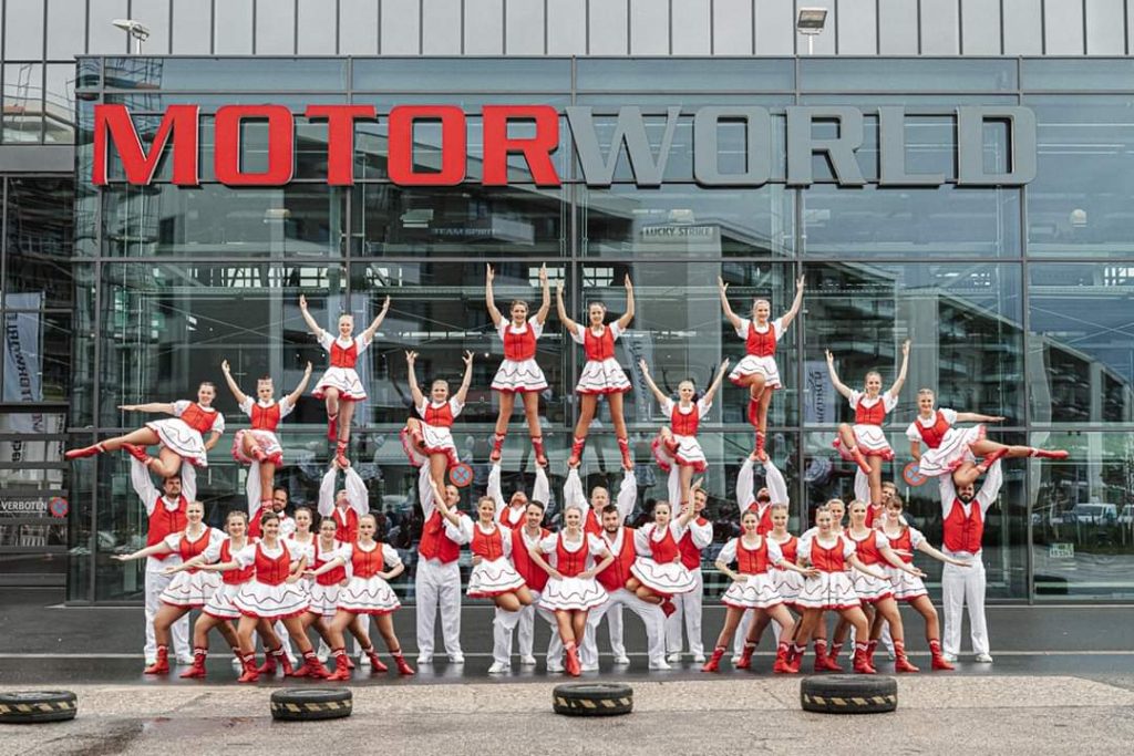 Cheerleaders in red and white uniforms in a formation in front of MotorWorld