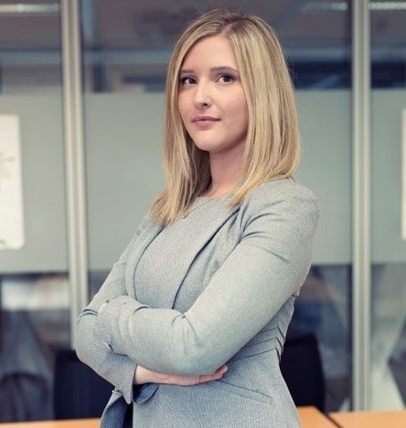 Woman in grey suit standing with arms crossed