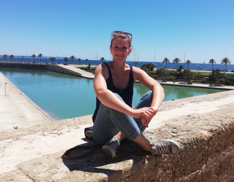 Girl sitting on concrete ledge near water